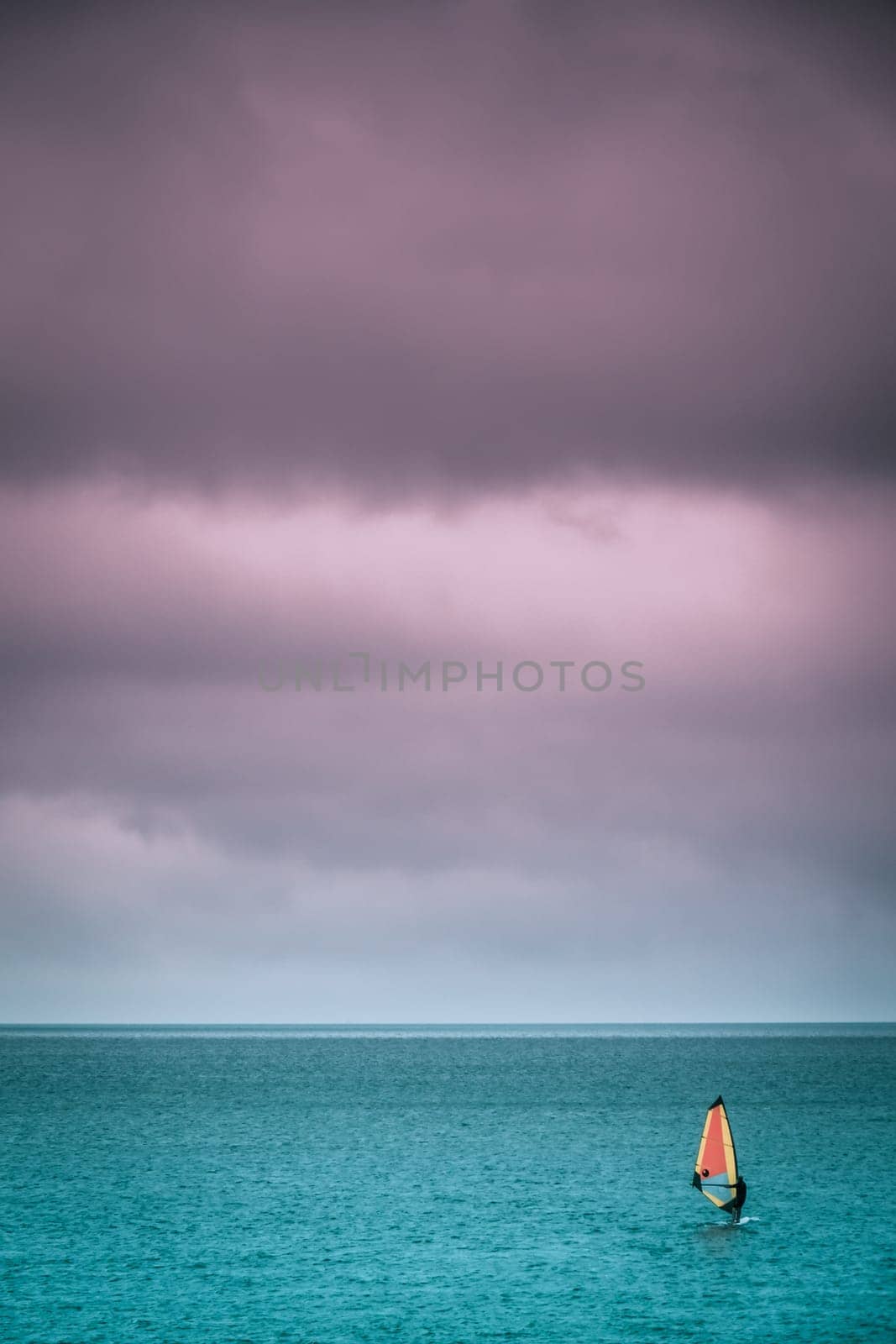 Single man windsurfing on a surface of a sea in Devon, England