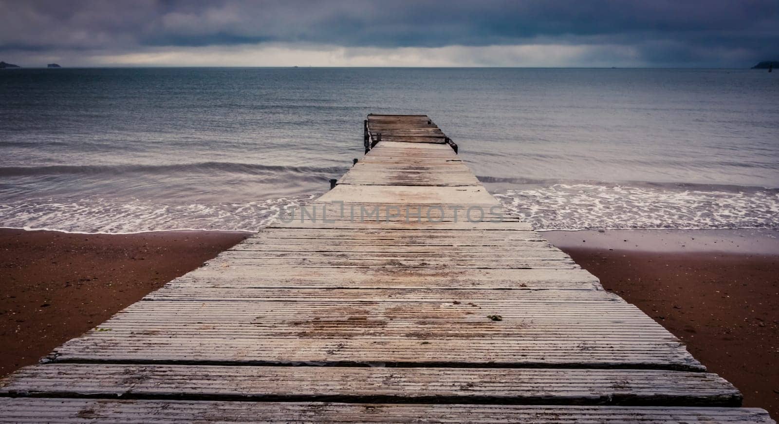 Small wooden pier leading into the sea in Paignton, Torbay, Devon, UK