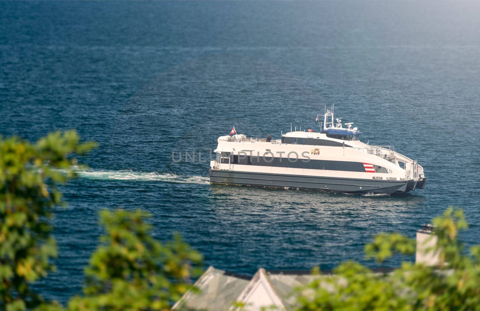 Ship in waters of fiord, Norway, Scandinavia, Europe. Blue and white waves.