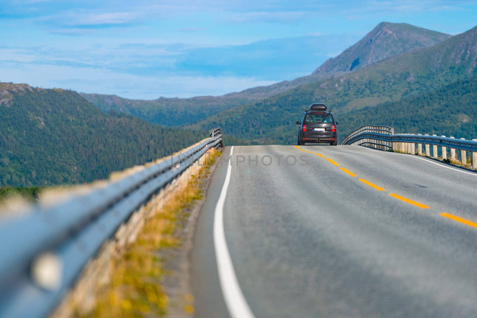 Car on mountain road in Norway, Europe. Auto travel through scandinavia. Blue sky and mountains in background.