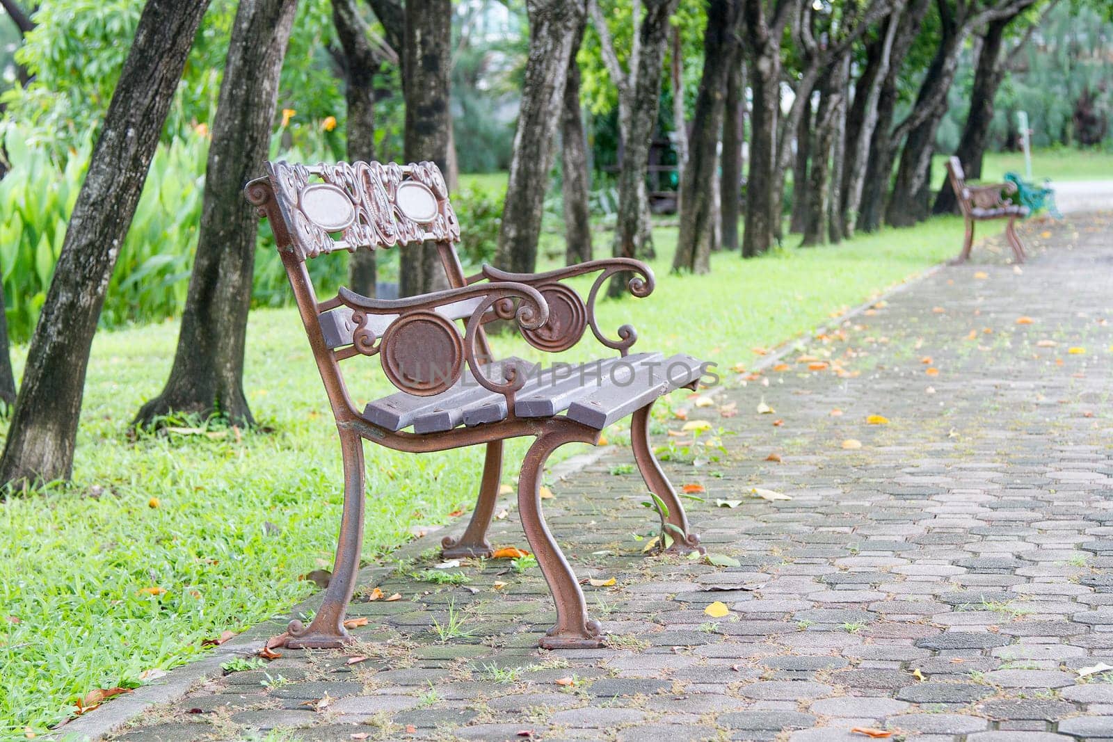 Steel long chair in the park with grass and brick blocks.