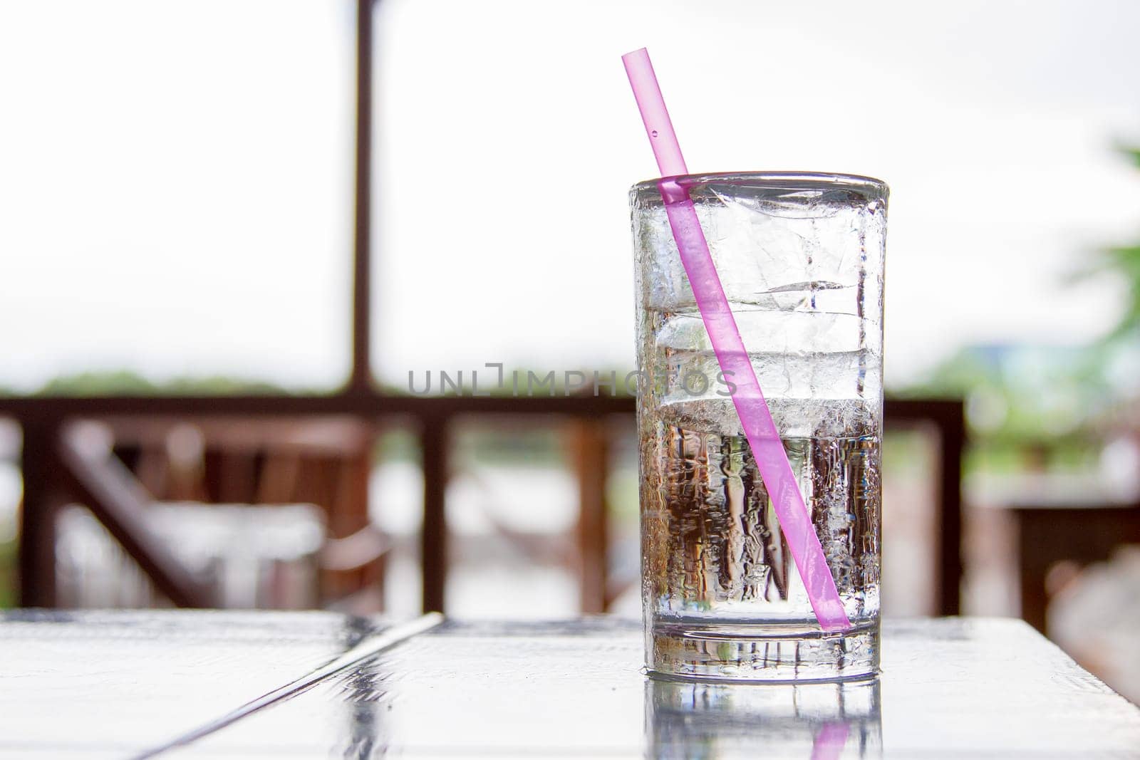 Ice glass placed on a wooden desk. With a pink tube