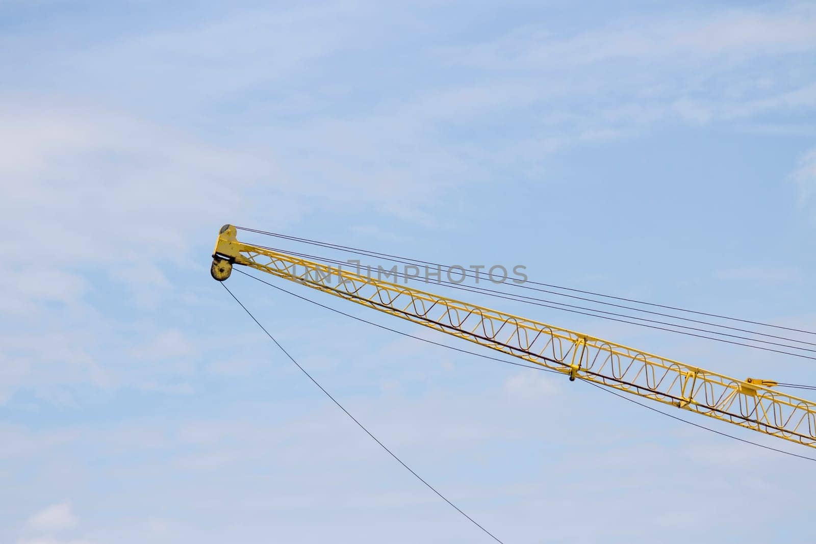 Crane lifts old yellow with blue sky.