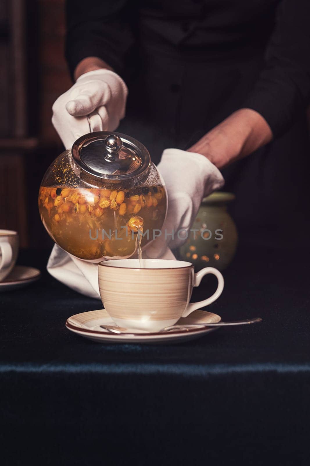 Pouring tea with sea buckthorn honey and herbs in glass teapot