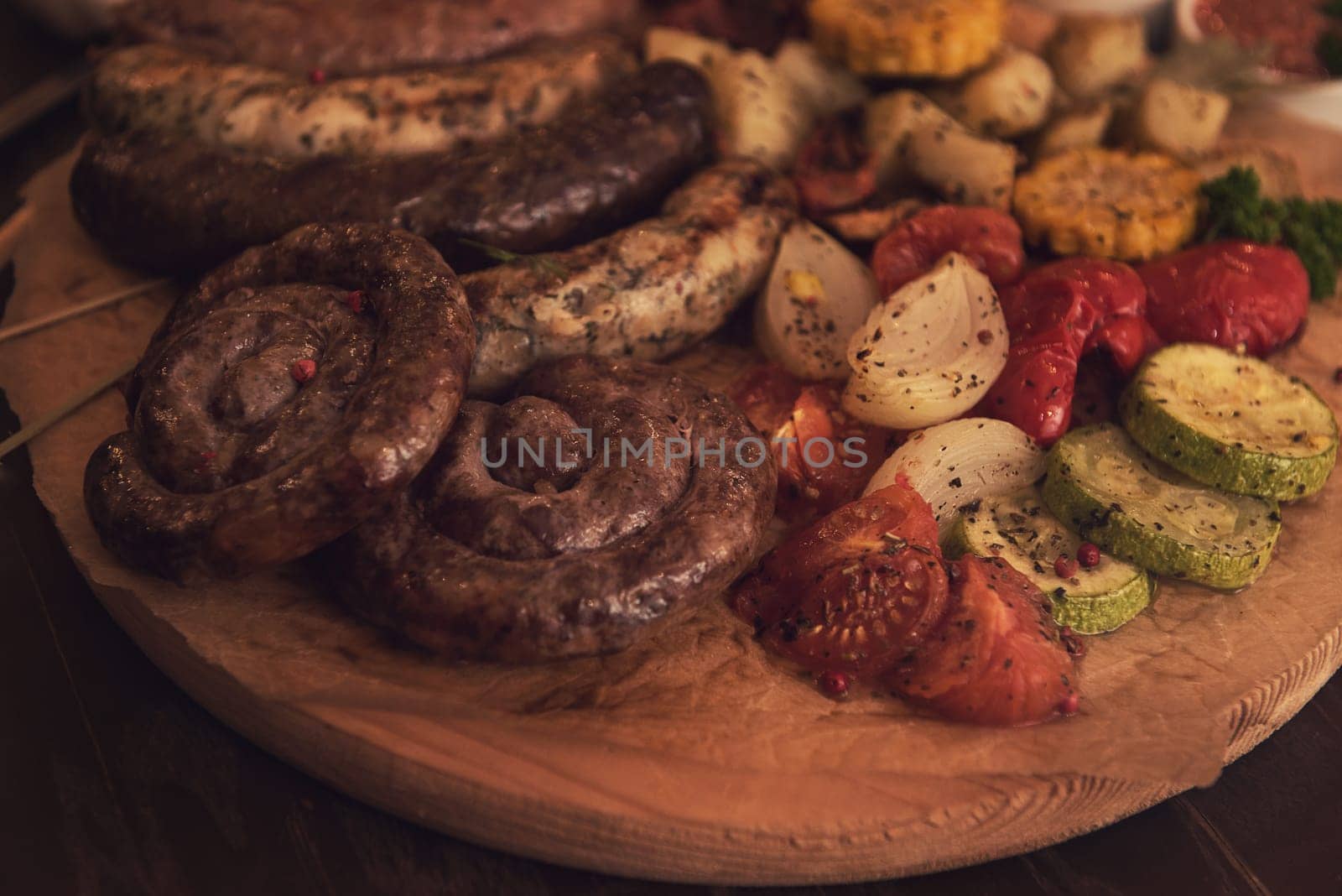 Grilled different meat and fish sausages with vegetables and spices on wooden background