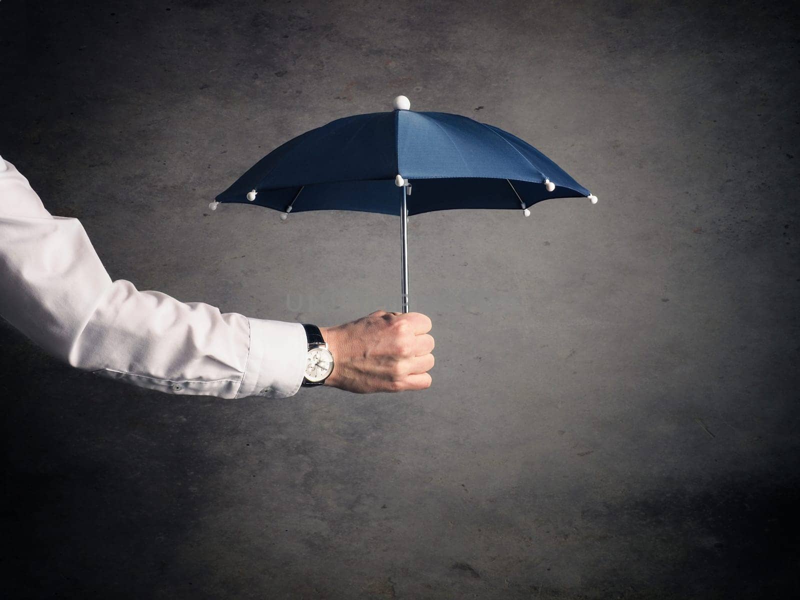 Businessman holding a small blue umbrella, protection or security concept image