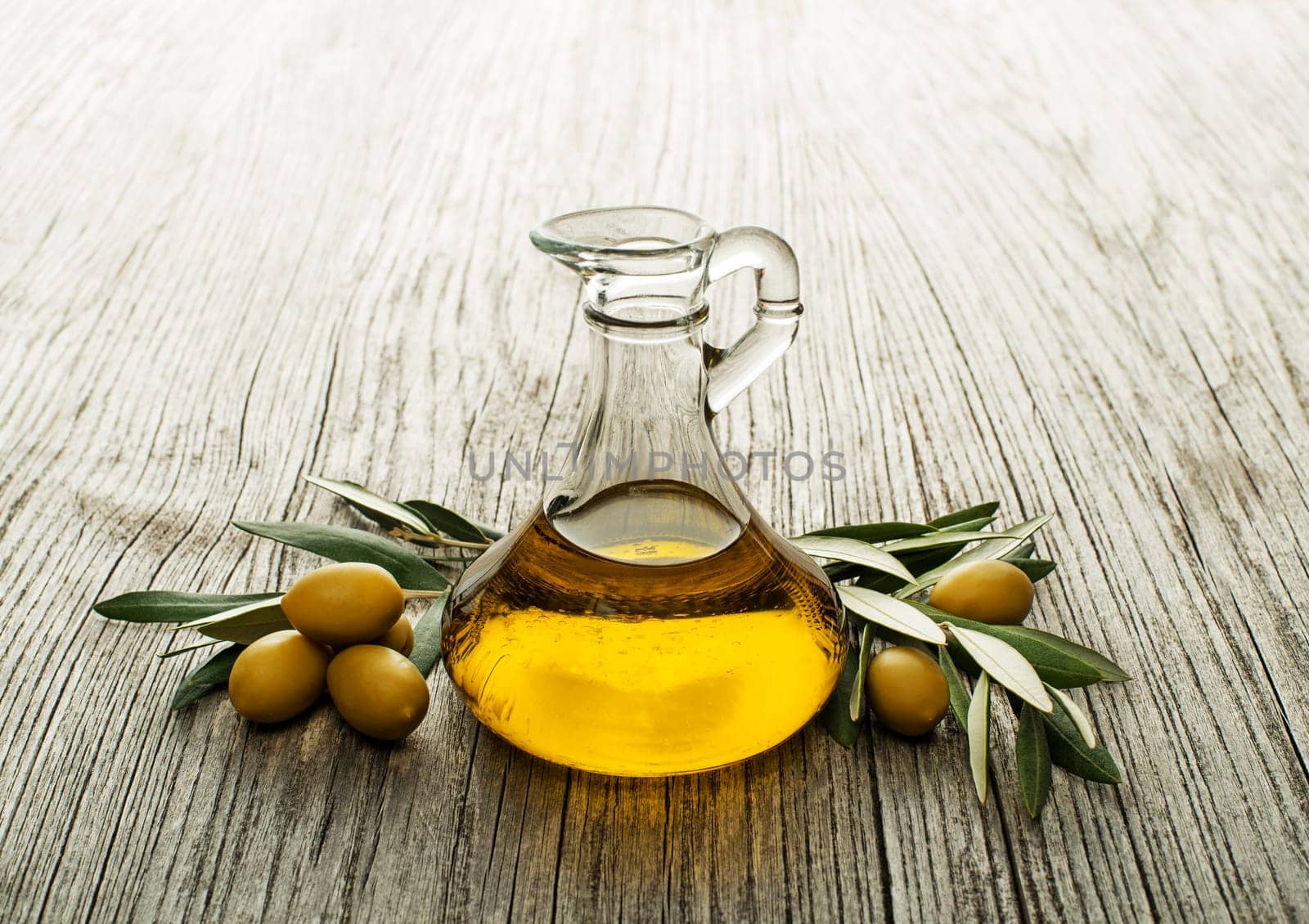 Olive oil and olive branch on wooden table