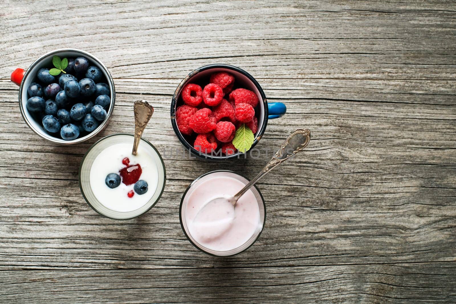 Yogurt with fresh berries in a glass jars with spoons