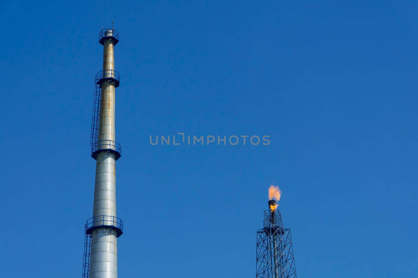 Gas flares in petroleum refinery  with blue sky background