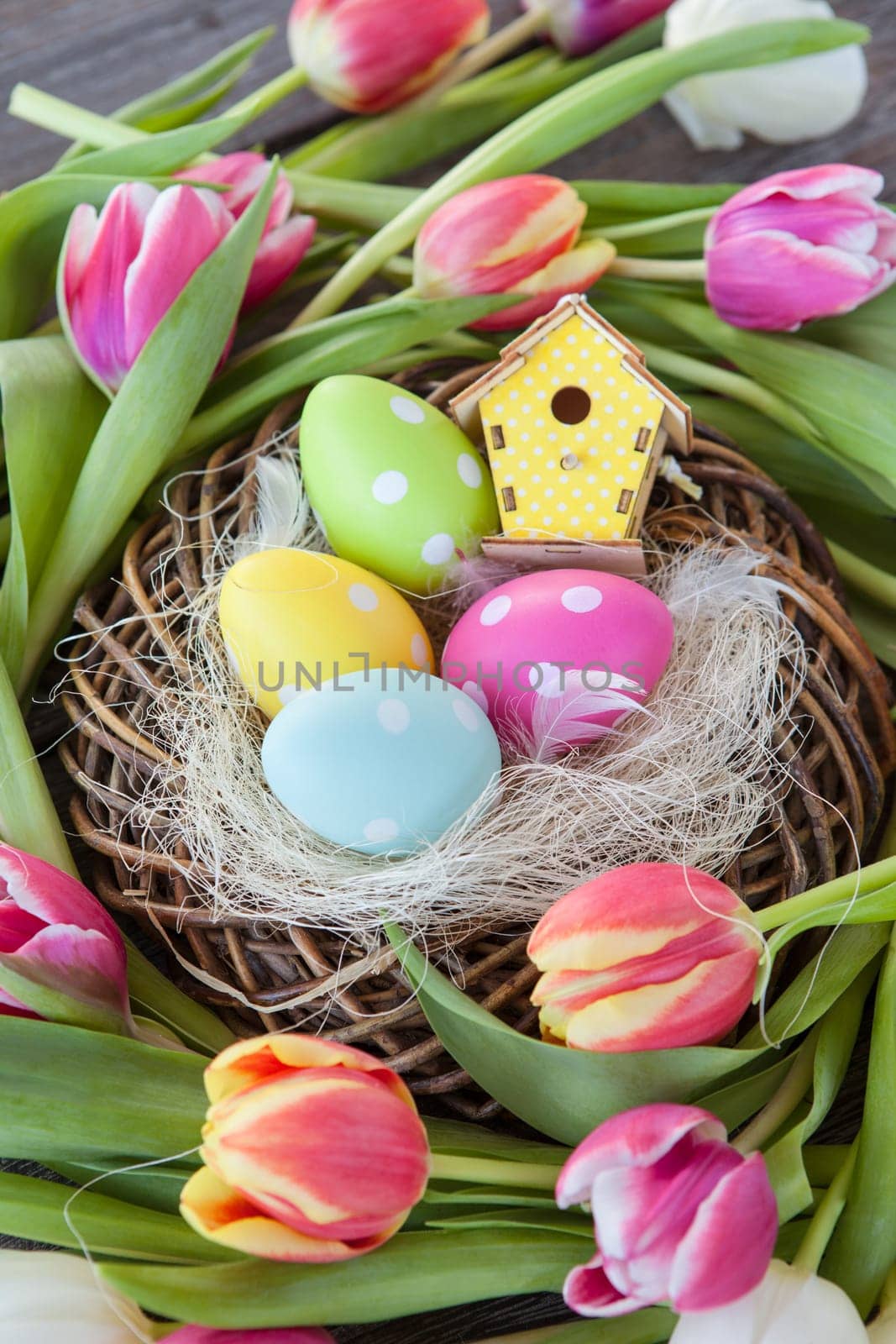 Small Easter nest with colorful eggs and tulips