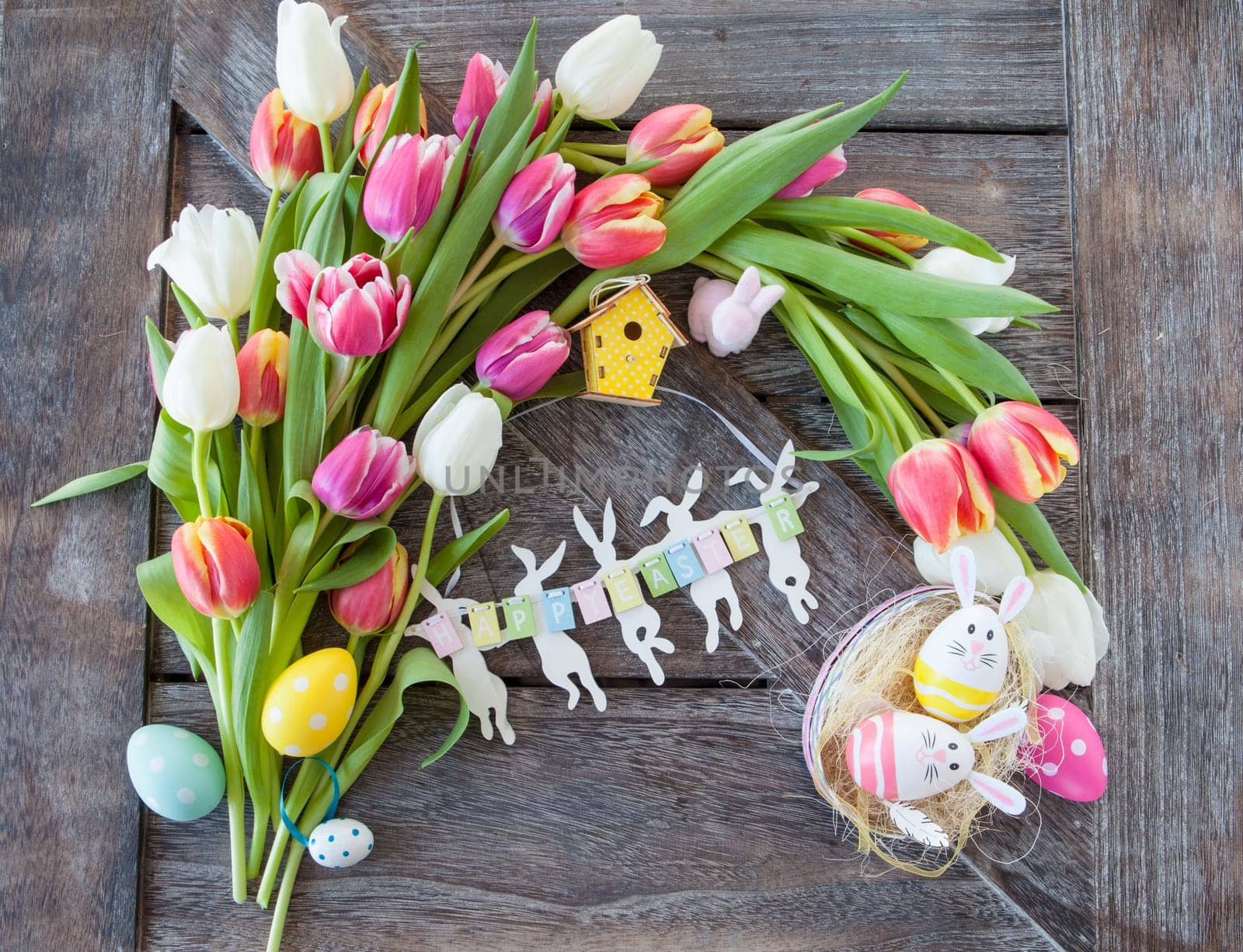 Small Easter nest with colorful eggs and tulips