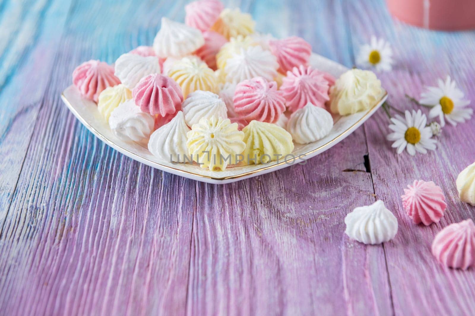 Tasty different marshmallows with chamomile flower on a color gradient background