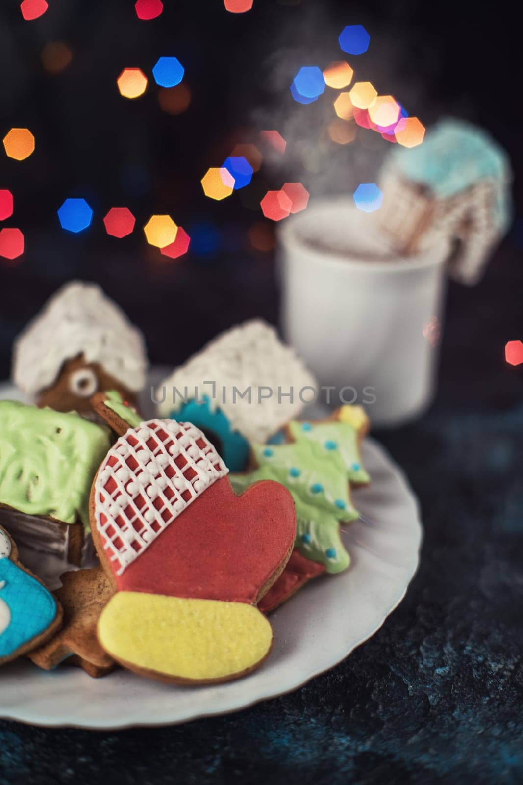 Christmas cookies and cup of tea on dark color bokeh lights background