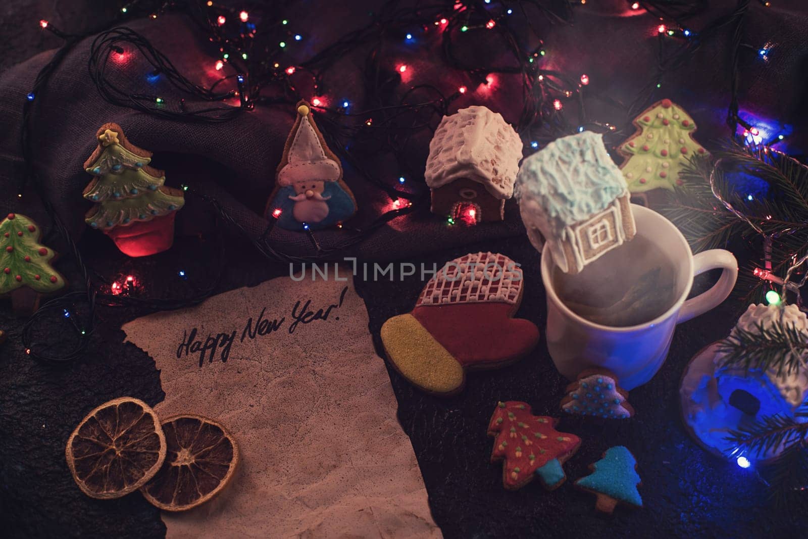 Christmas cookies and cup of tea on dark color bokeh lights background