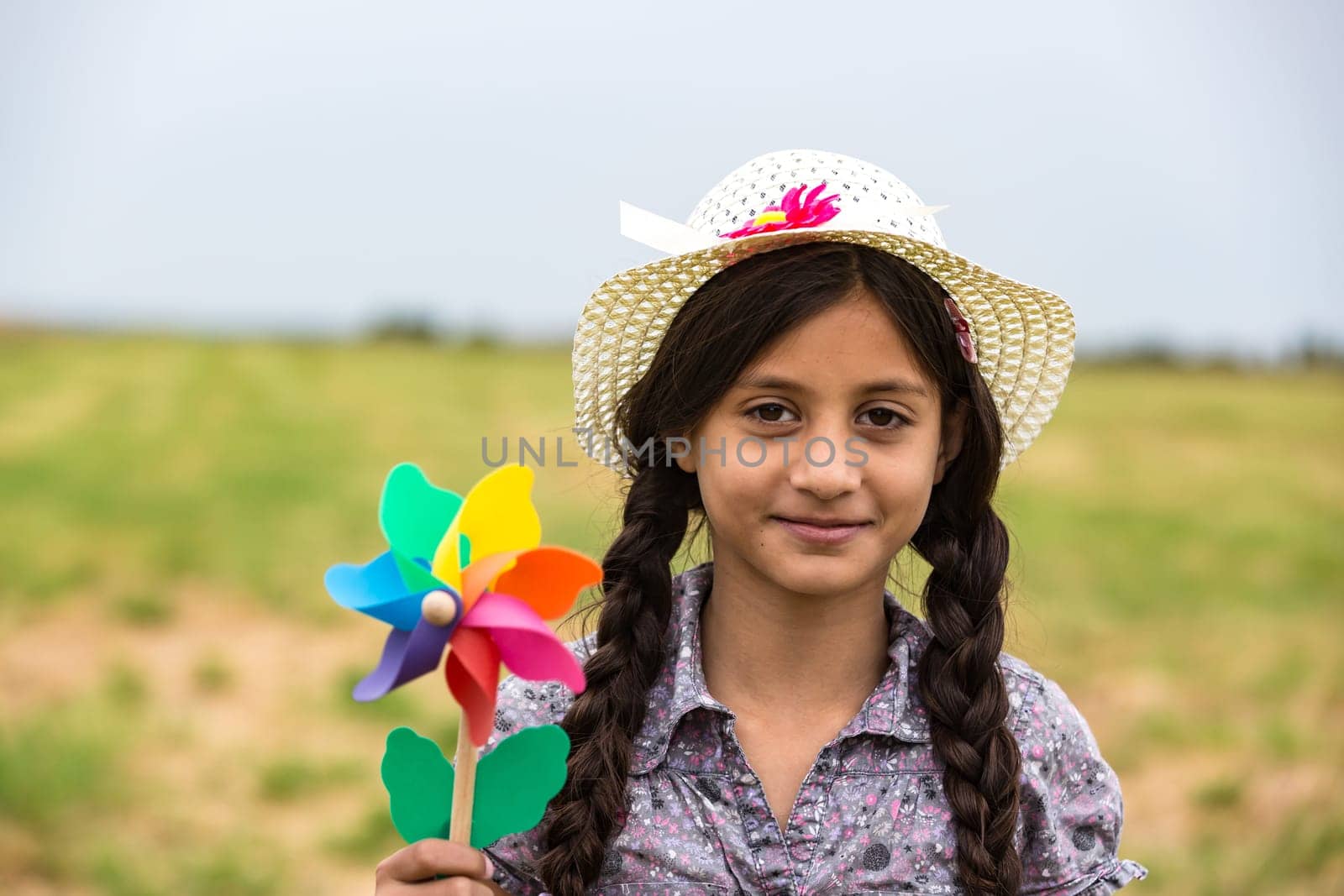 Happy girl blows into wind turbines of a colorful wind turbine