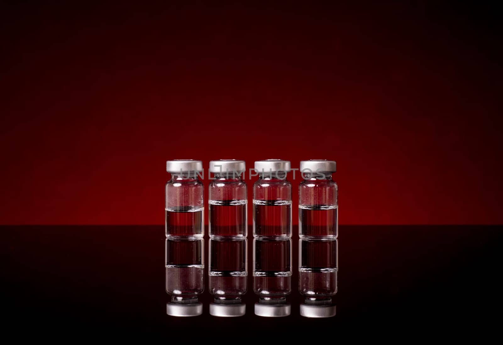 Medical Vials with clear liquid isolated og red black background