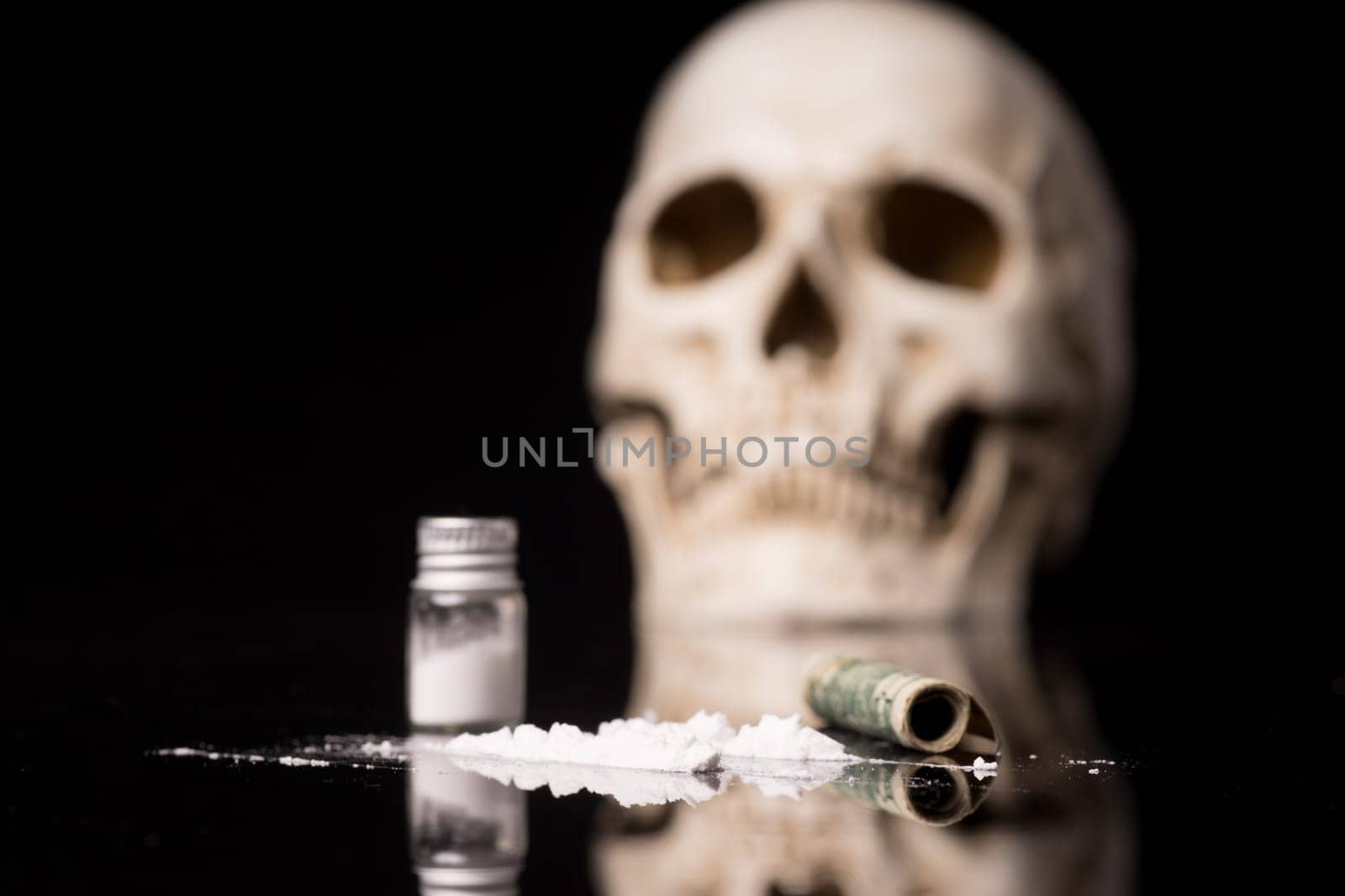 cocaine or other illegal drugs that are sniffed by means of a tube and Skull, isolated on black glossy background