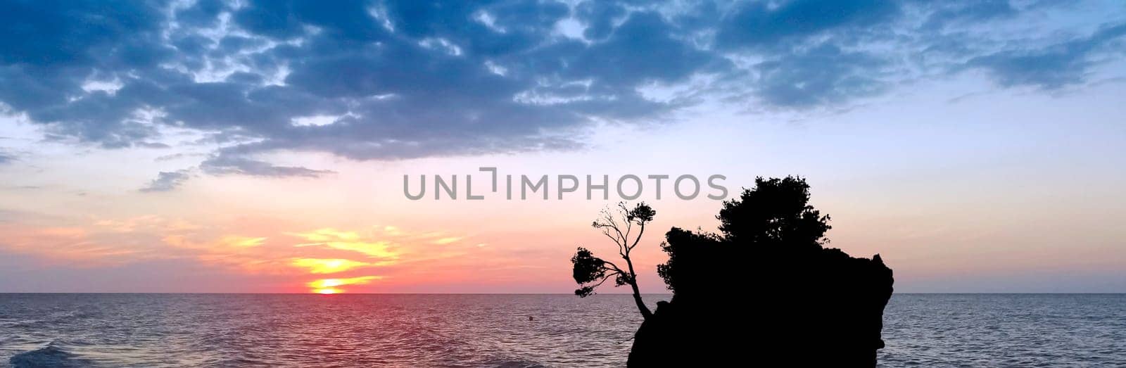 Dramatic sunset over the Adriatic Sea with Kamen Brela - Tiny famous island in Brela, Makarska Riviera, Croatia