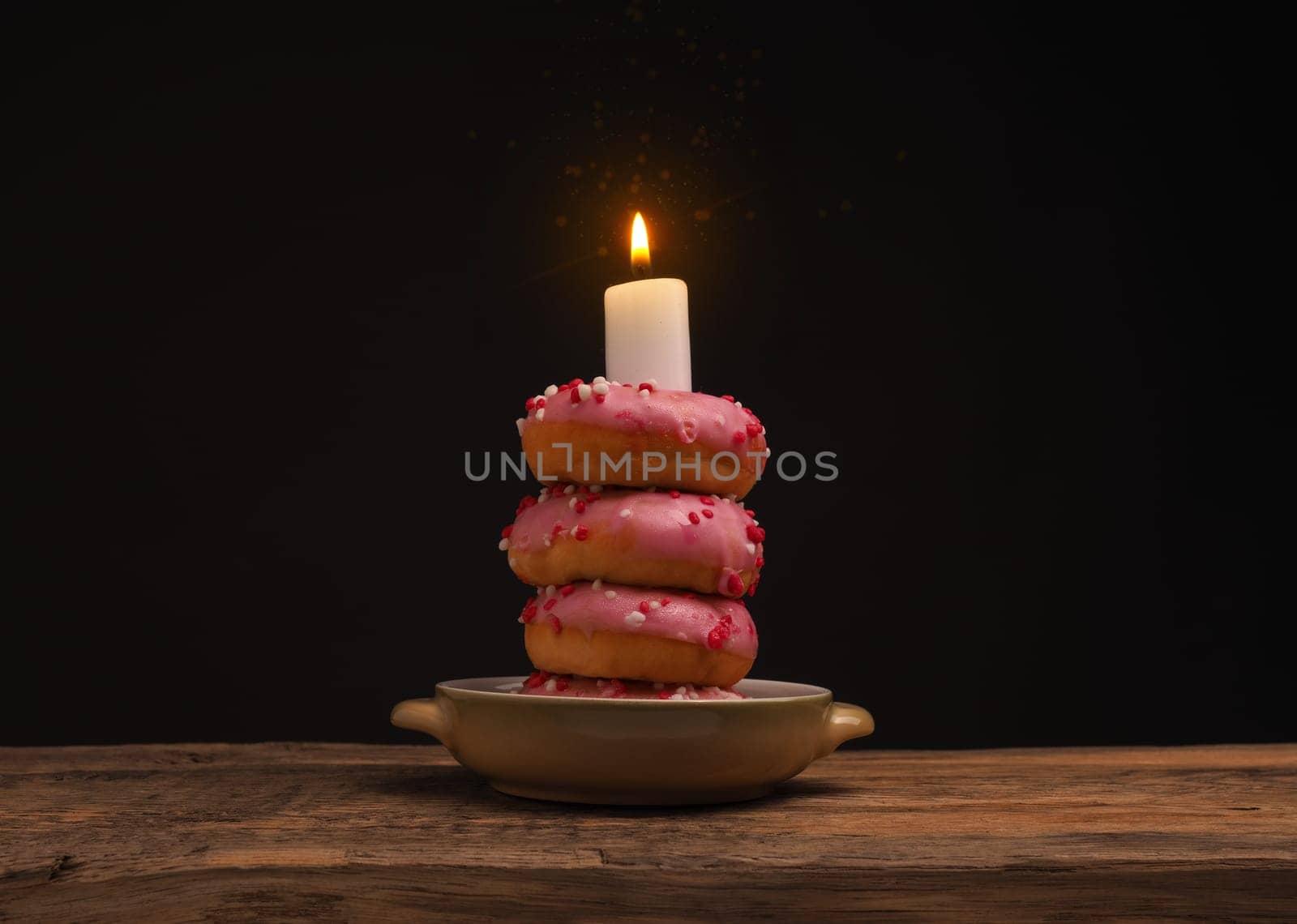 Birthday cake with stacked donuts and a burning candle