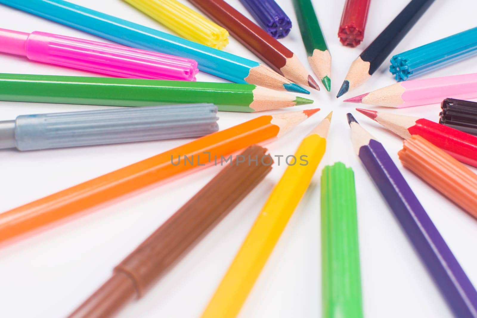 Colorful wooden pencils and felt pens are in circle on white background. Drawing tools.