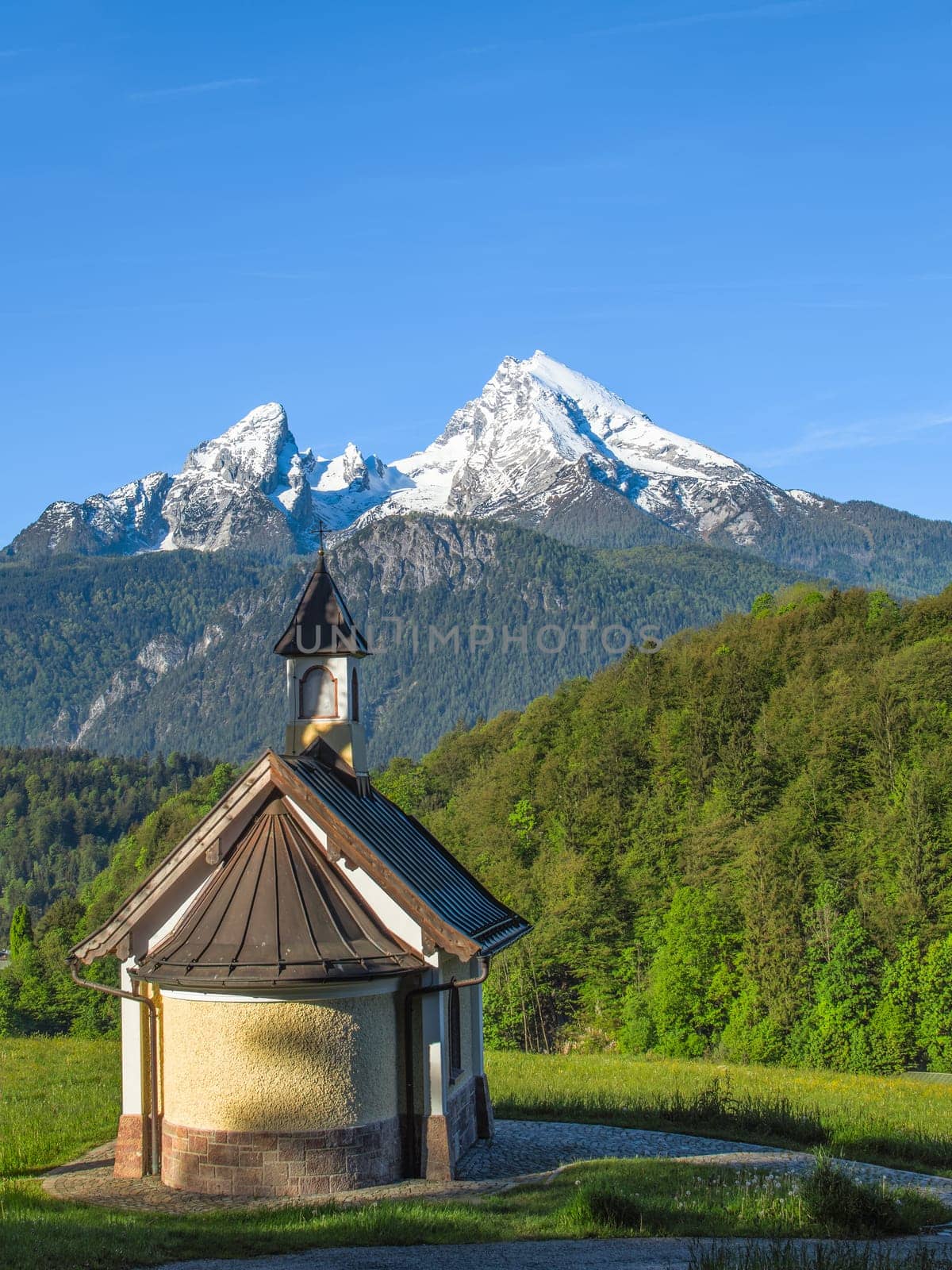 Vertical view of small chapel and snowy summit of Watzmann mountain in Bavarian national park Berchtesgaden