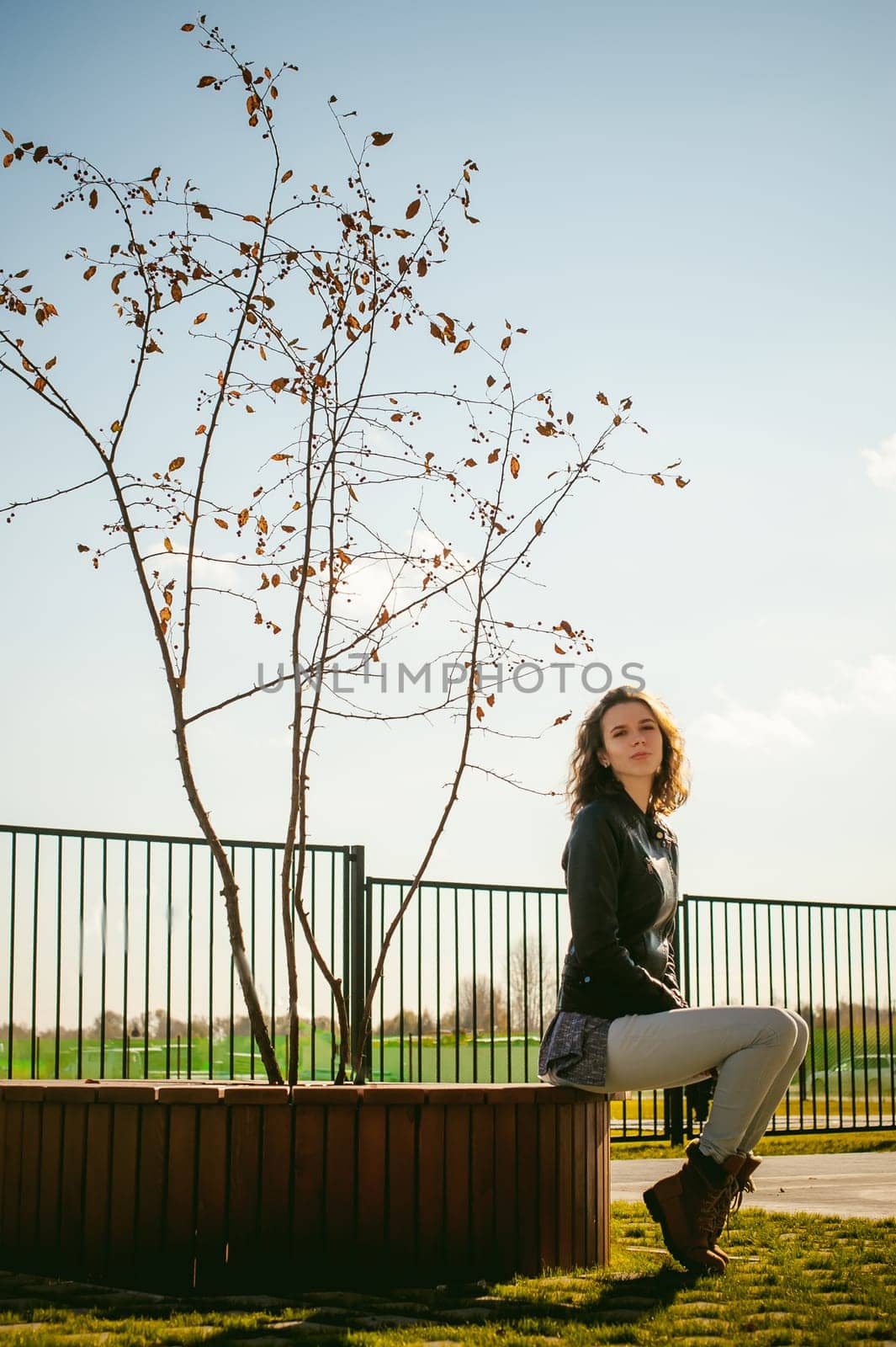 Portrait of young woman walking outdoors on warm autumn afternoon. Sitting resting