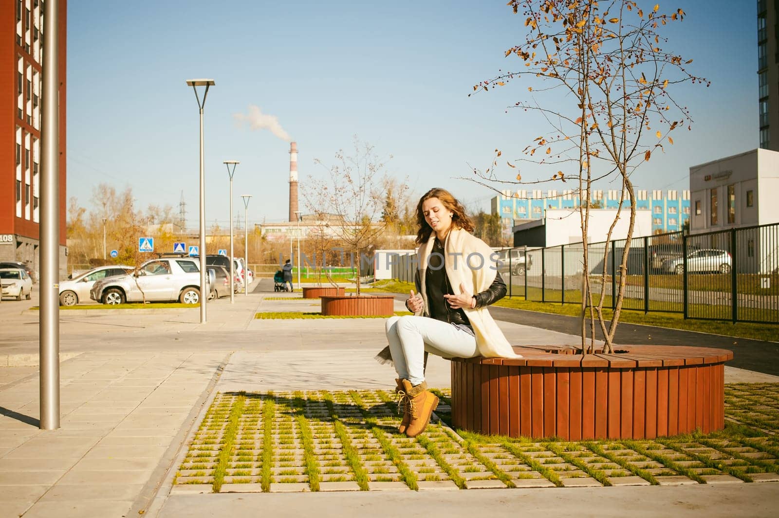 Portrait of young woman walking outdoors on warm autumn afternoon. Sitting resting
