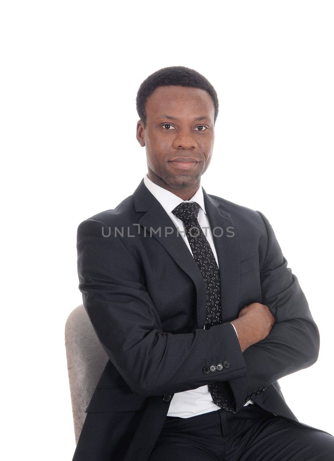 A portrait image of a serious handsome business man sitting with his.arms crossed, looking into the camera, isolated for white background.