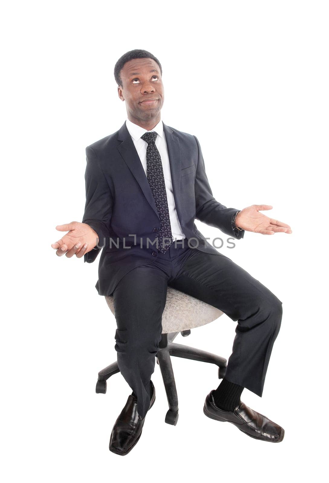 A handsome young businessman sitting on an office chair with his .hands up, is frustrated, looking up, isolated for white background.
