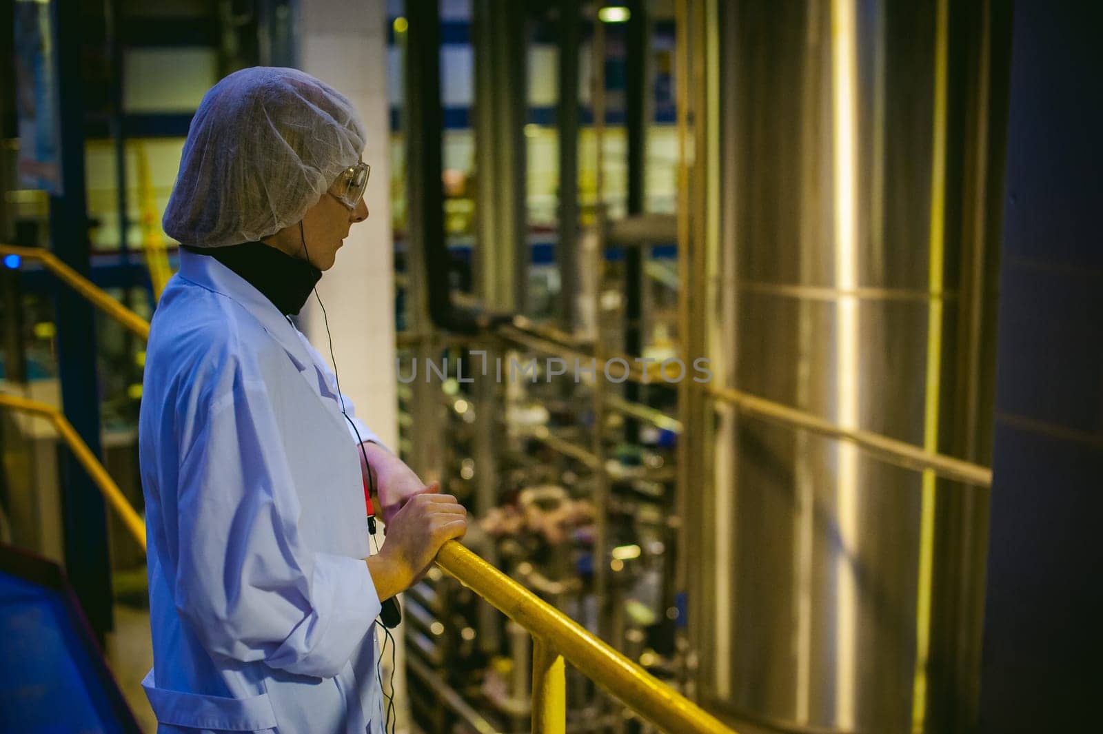 Female worker on the production line of beer factory. portrait of a woman in a white robe, standing on the background of the production line at the factory bottling of finished products