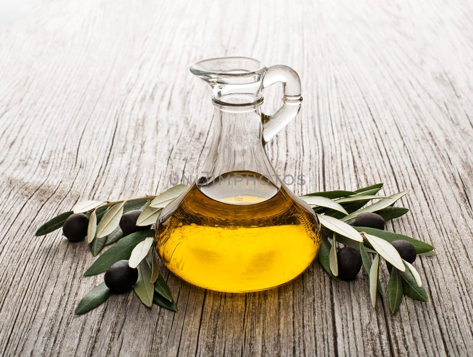 Olive oil and olive branch on wooden table