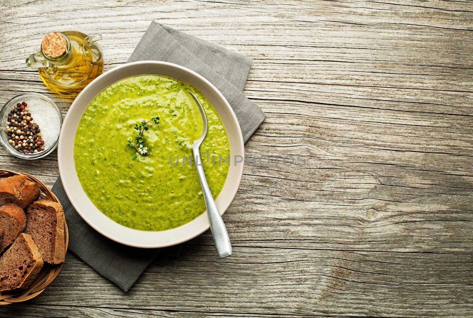 Fresh healthy green soup on wooden background overhead shoot.