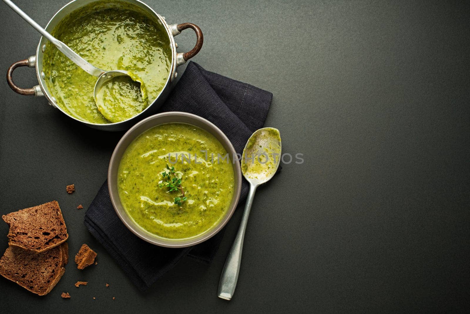 Fresh healthy green soup on black background overhead shoot.