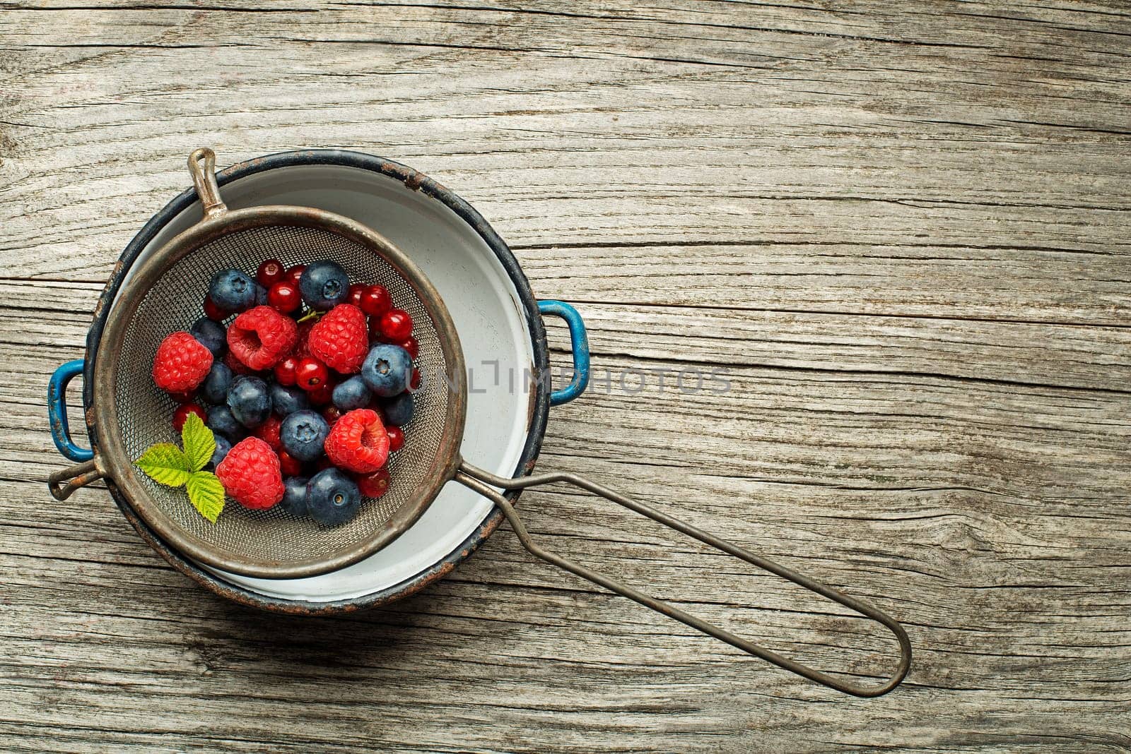 Mix of fresh berries in a bowl on wooden background