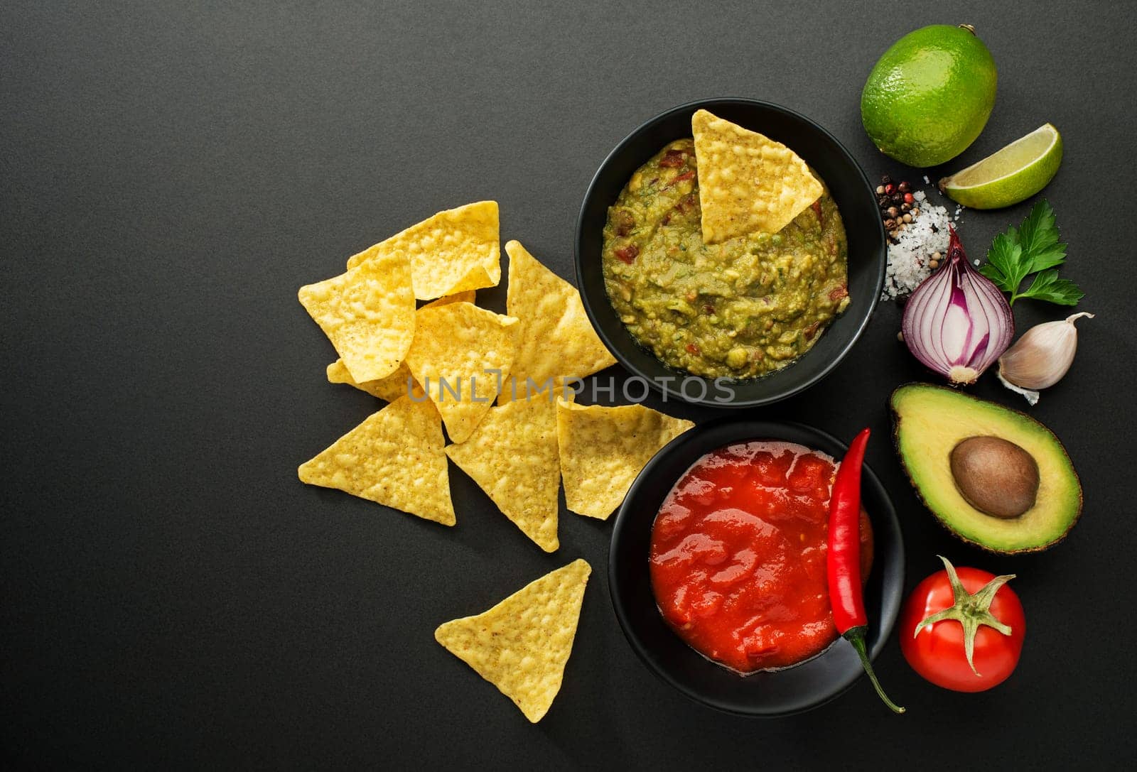 Avocado guacamole and tomato salsa with fresh ingredients on table