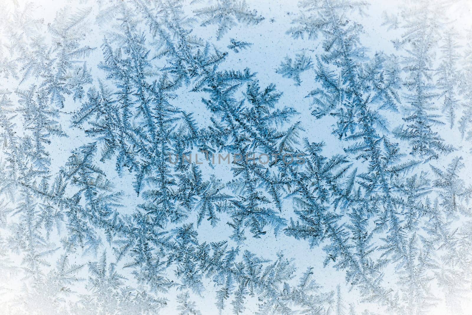 Macro photo of frozen ice crystals on glass as winter texture background.