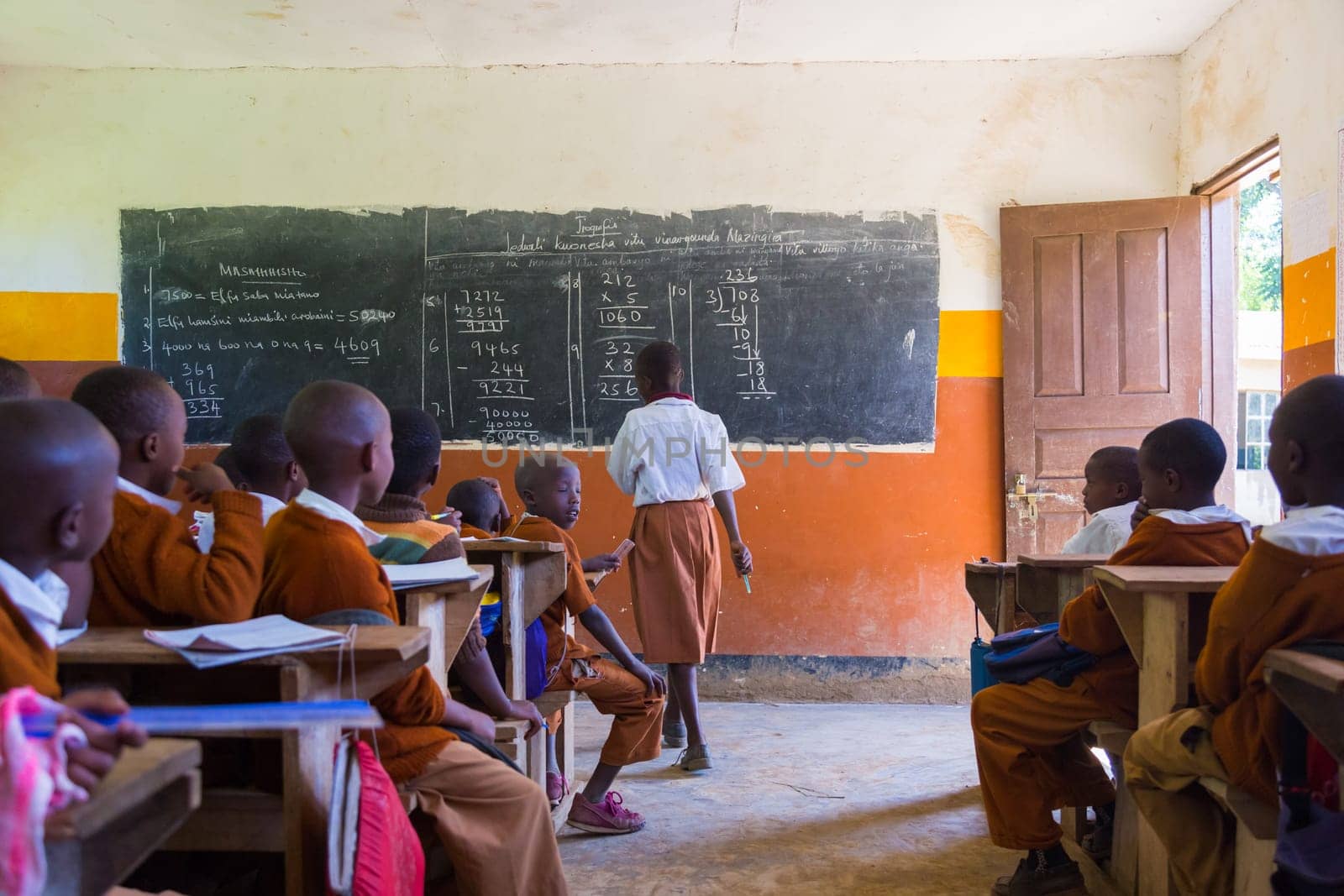 Arusha, Tanzania- Jan 26, 2015: Children in uniforms in elementary school classroom sitting behind desks listetning to teacher on January the 26th, rural area near Arusha, Tanzania, Africa.