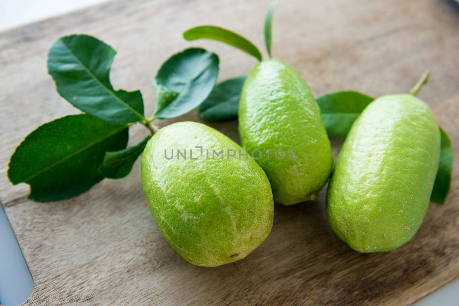 Pesticide free fresh organic lemons with leaves on wooden table background, imperfect insect bites.