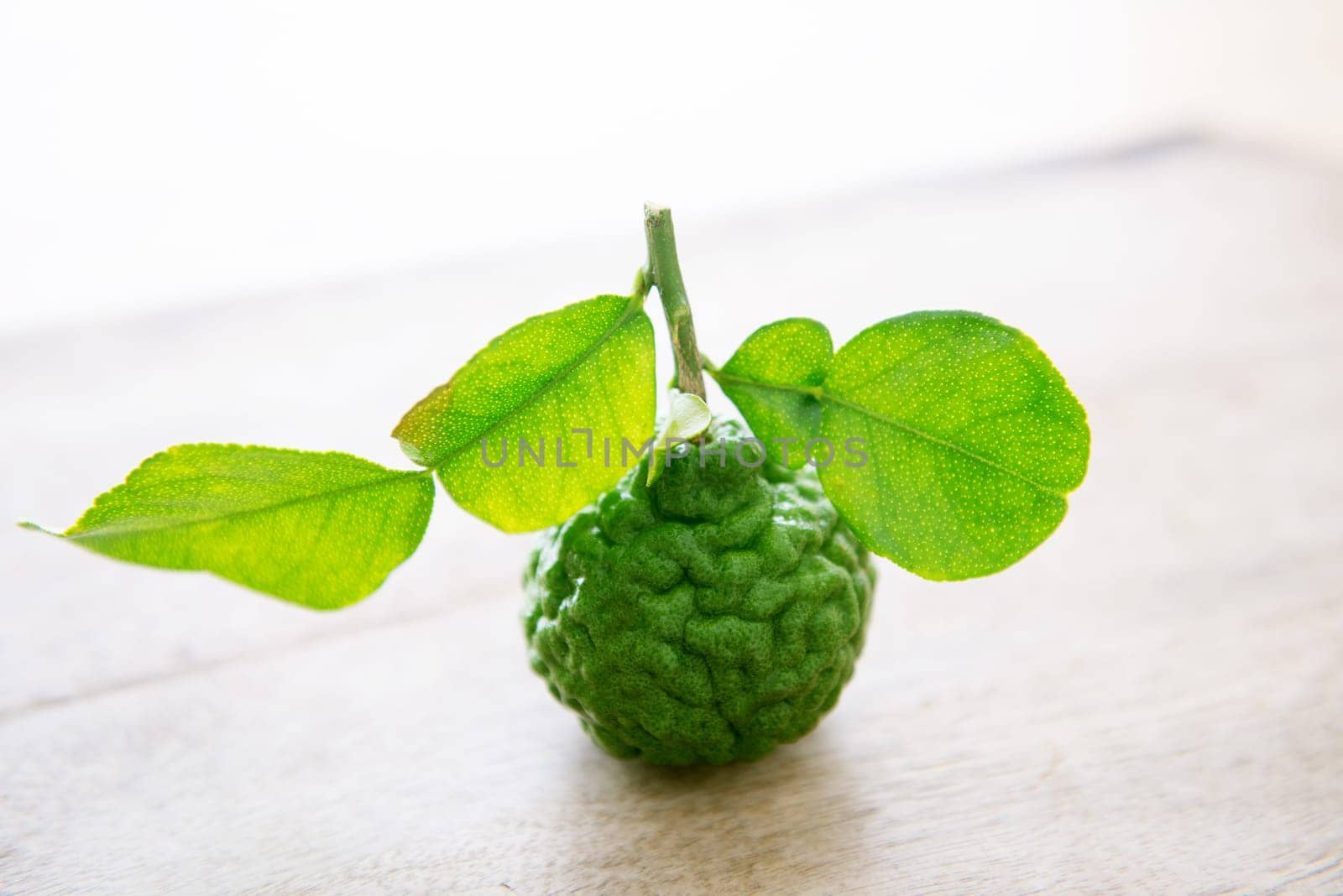 Fresh organic kaffir lime with leaves on wooden background.
