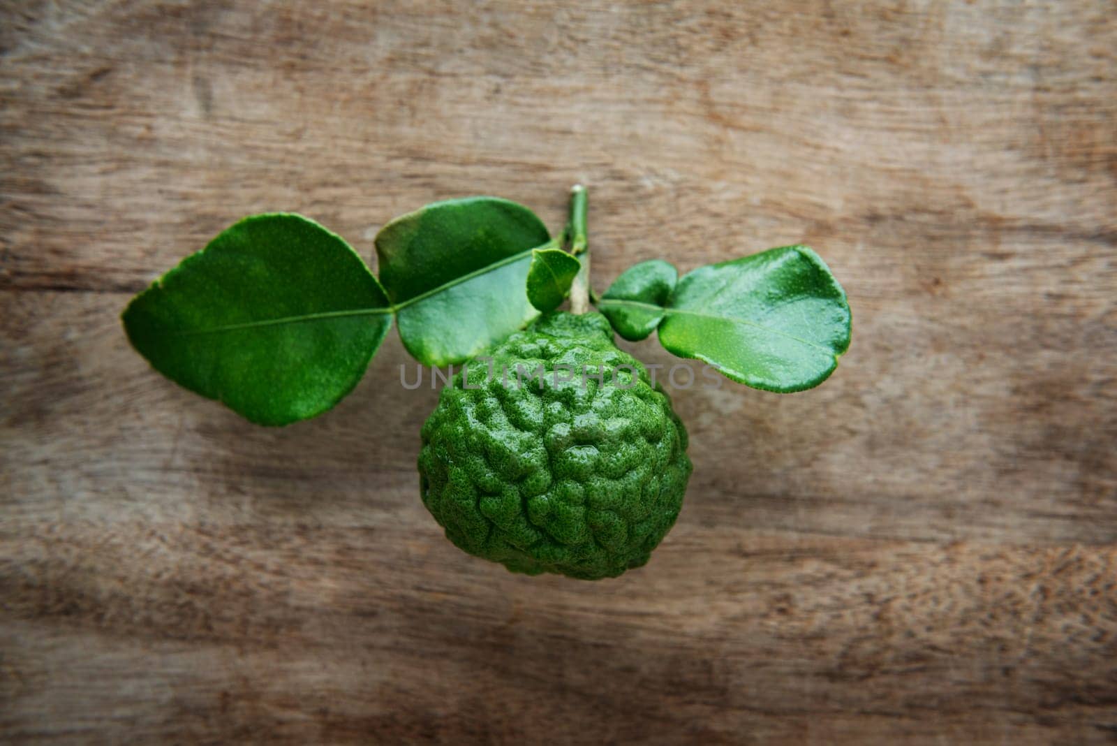 Top view pesticide free fresh organic kaffir lime with leaves on wooden background.