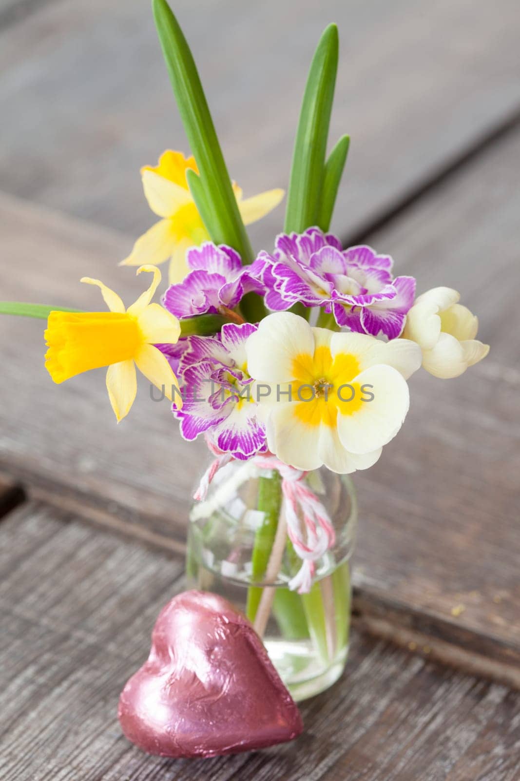 Colourful bouquet of spring flowers in a small bottle