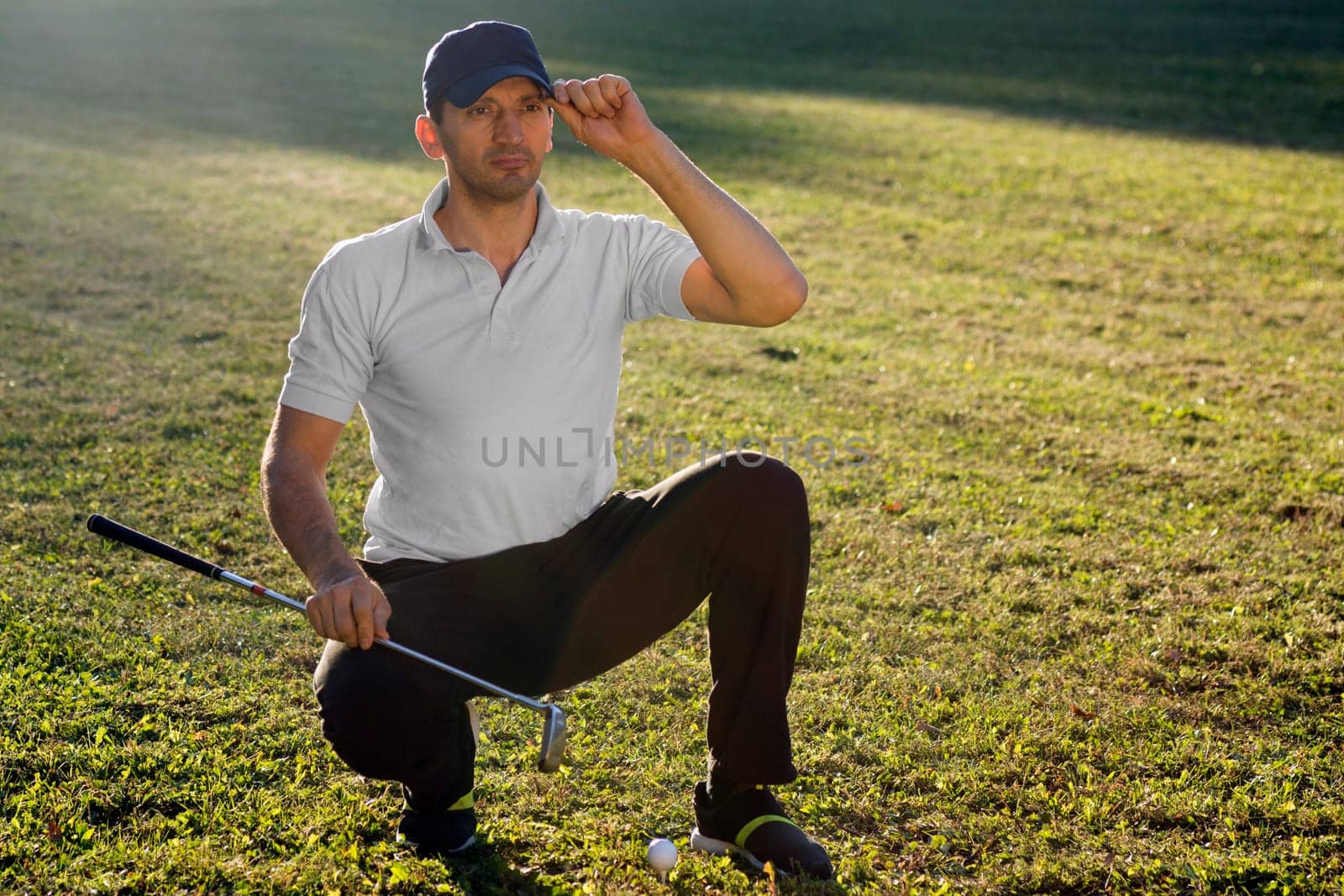 Portrait of handsome golfer with golf club and ball outdoors on playing field.