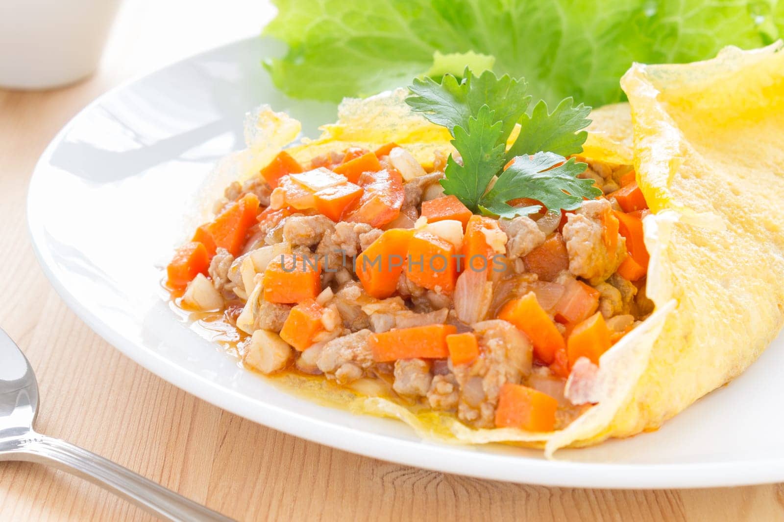 Stuffed omelet with carrot pork onion lettuce coriander in white dish. Stuffed omelet food. Delicious stuffed omelet or fried eggs for breakfast. Stuffed .omelet or fried eggs for health care people.