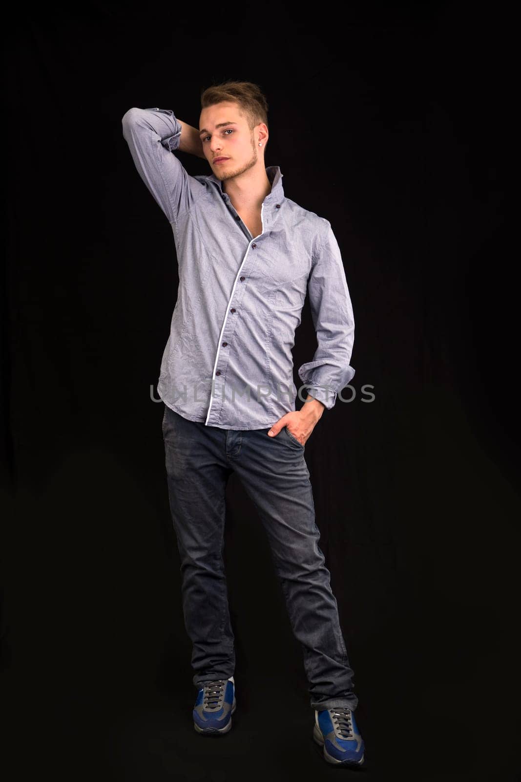 Full length portrait of handsome blond young man on dark background