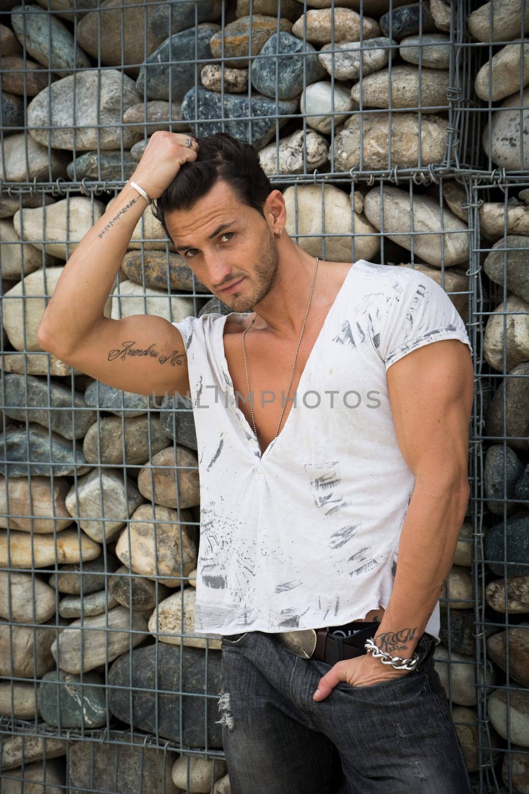 Handsome man outdoor in front of stone wall looking at camera