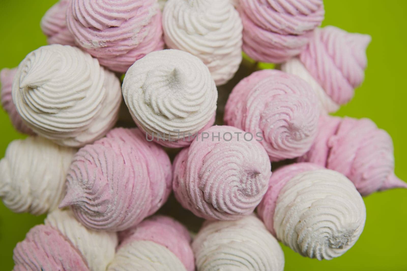 Delicious sweet buffet with homemade pink and white zephyr. Russian marshmallows. On a green background, selective focus