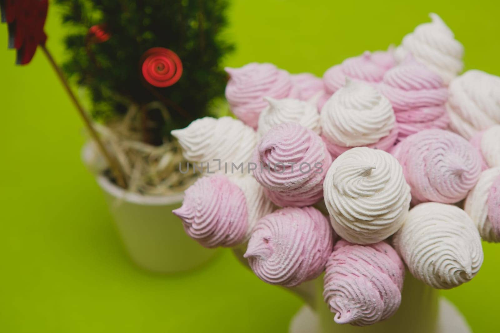 Delicious sweet buffet with homemade pink and white zephyr. Russian marshmallows. On a green background, selective focus