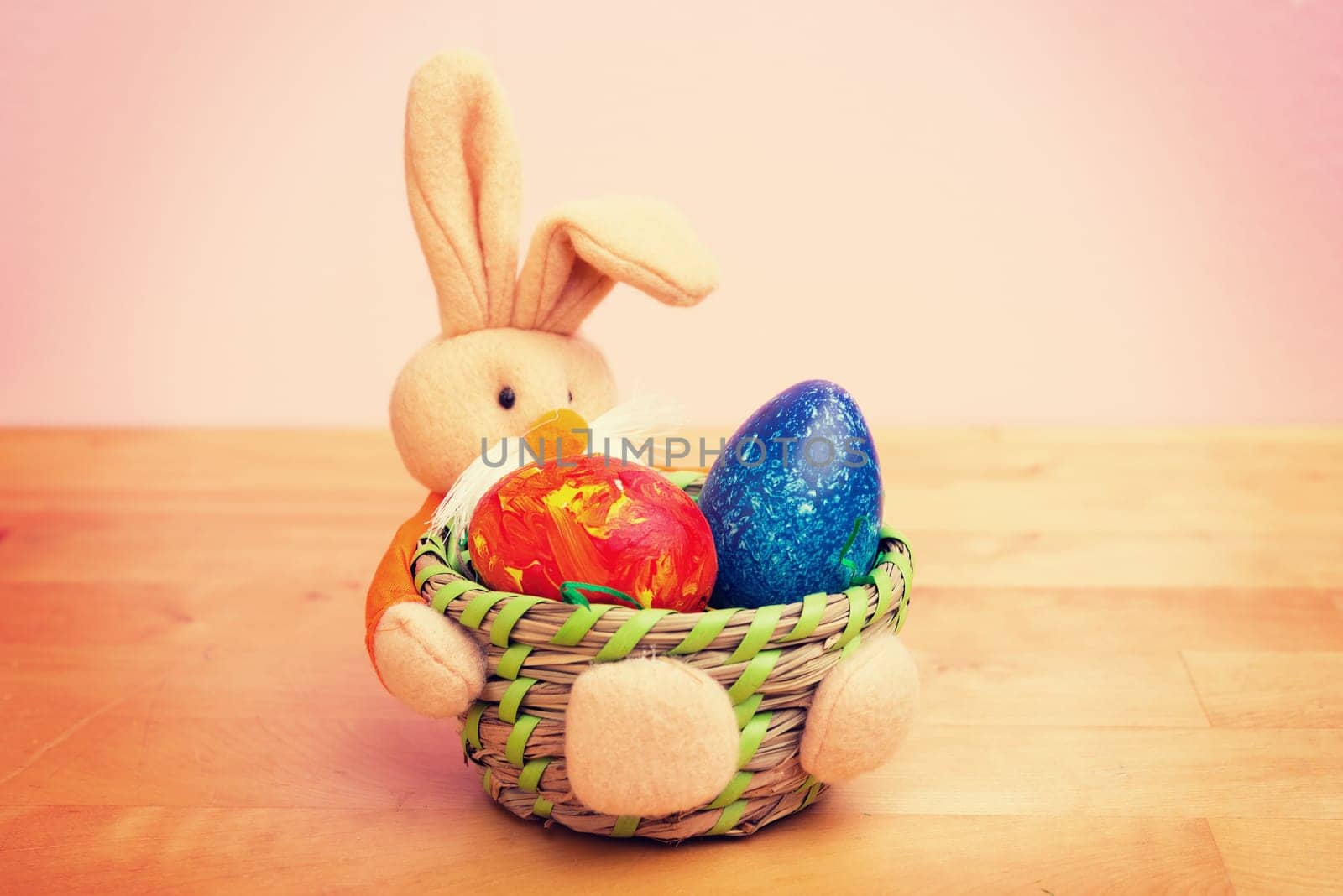 easter bunny in basket with egg in front of pink background