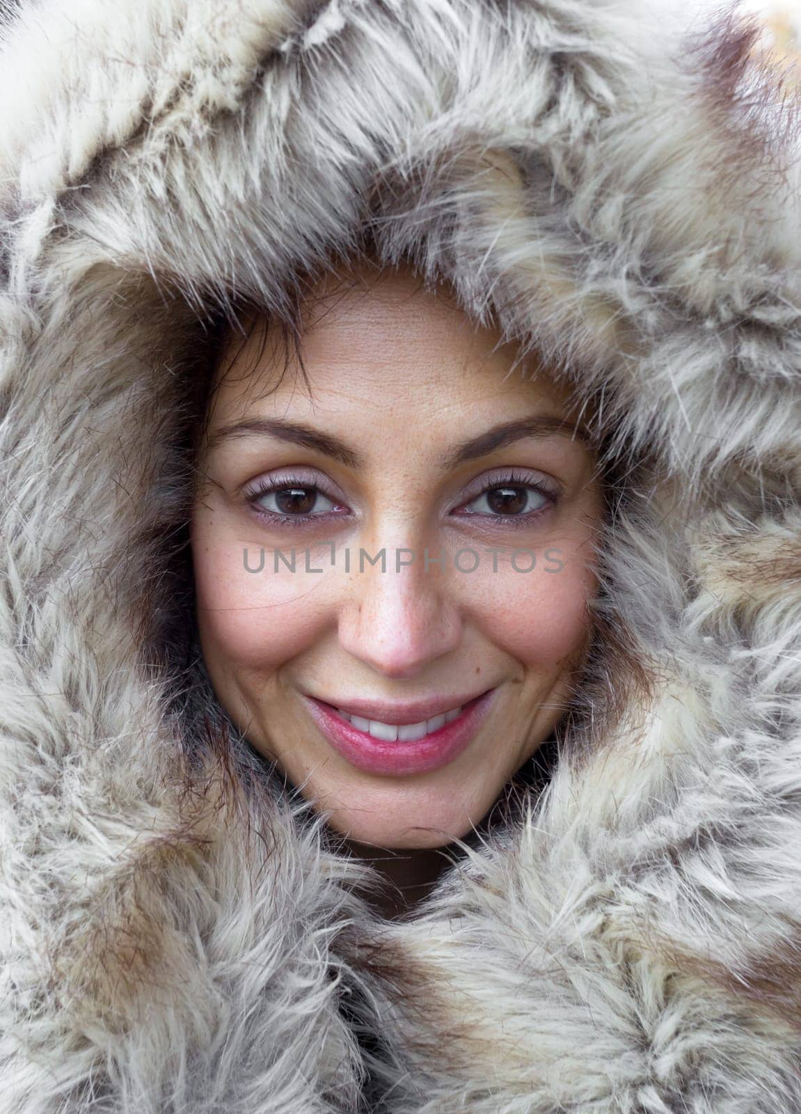 Portrait of cheerful and smiling girl  his face is framed by a fur hood. The make up is natural.