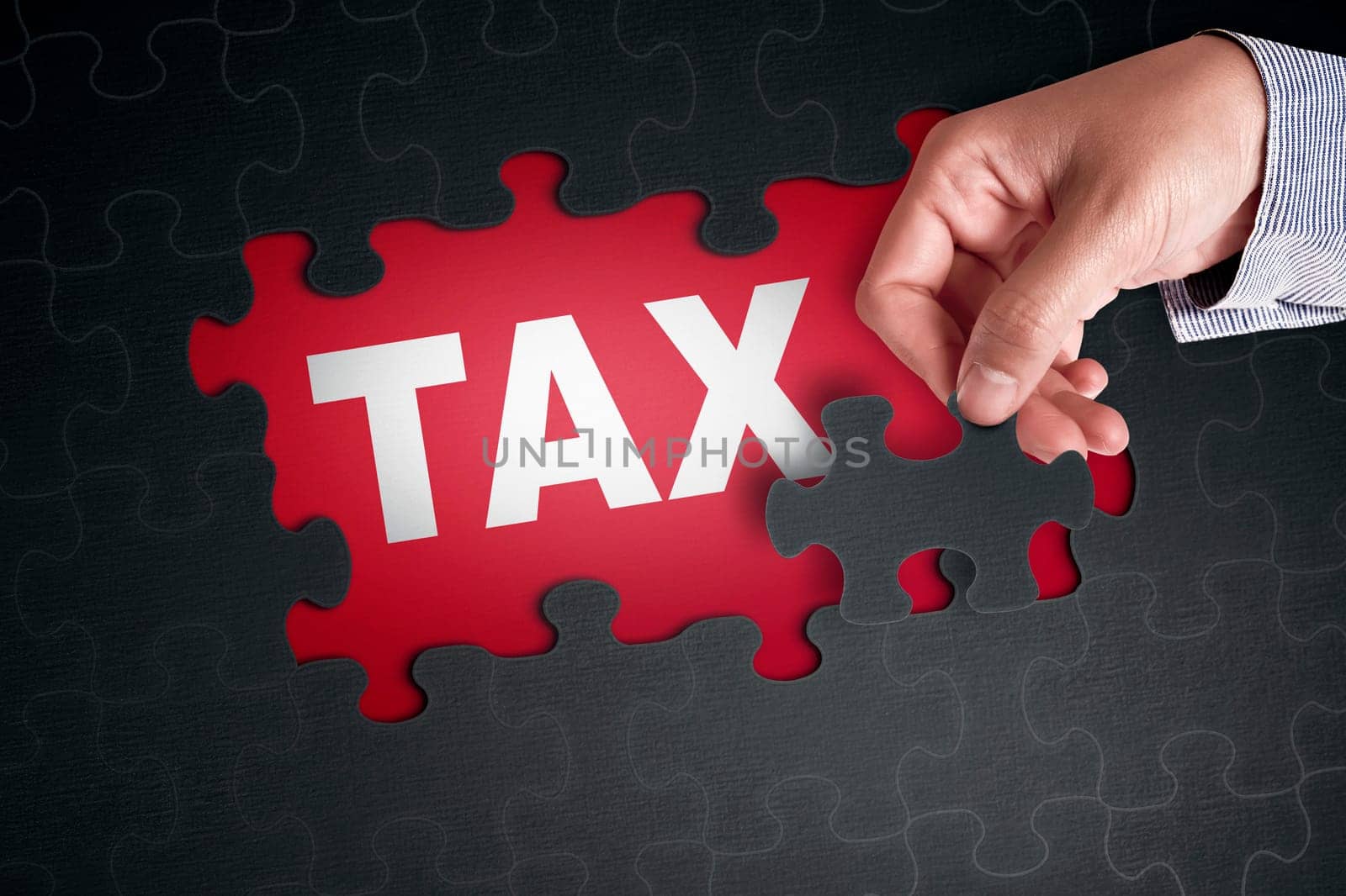 People hand placing puzzle piece with word TAX on red background